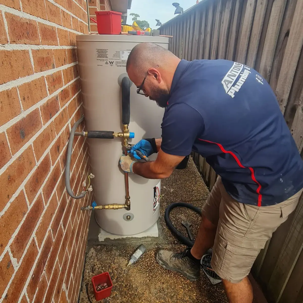 Ryde plumber working on pipe connections to an outdoor hot water storage tank