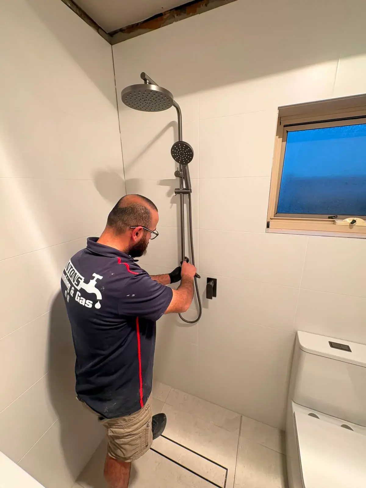 Ryde plumber from Antons fitting a shower rail in a renovated bathroom